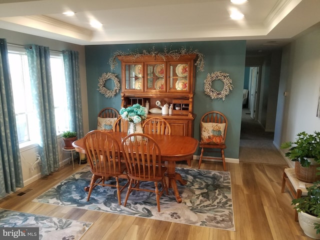 dining room featuring a tray ceiling, crown molding, and light hardwood / wood-style floors