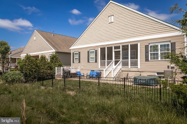 back of property with central AC and a sunroom