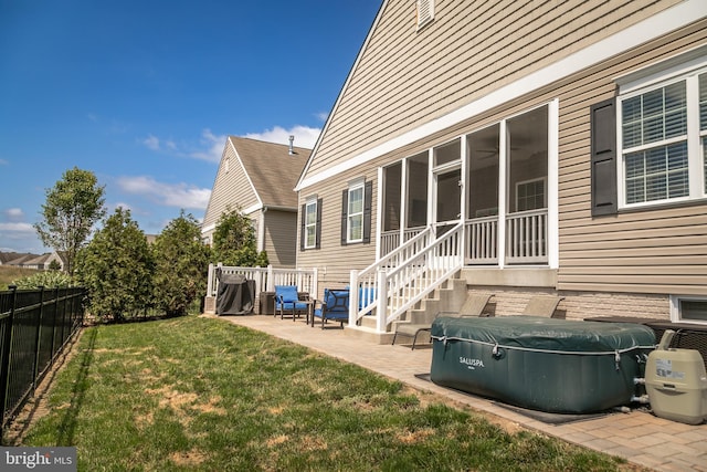 rear view of house featuring a patio, a sunroom, and a lawn