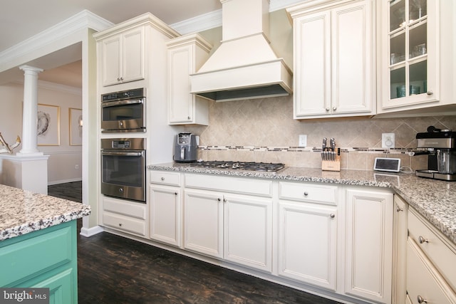 kitchen featuring custom range hood, stainless steel appliances, decorative columns, dark hardwood / wood-style flooring, and tasteful backsplash