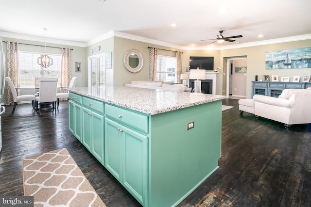 kitchen featuring a kitchen island, crown molding, green cabinetry, decorative light fixtures, and dark hardwood / wood-style flooring