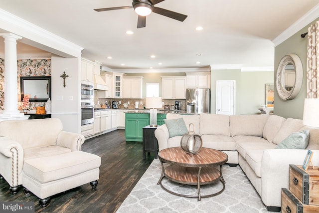 living room featuring decorative columns, ornamental molding, hardwood / wood-style flooring, and ceiling fan