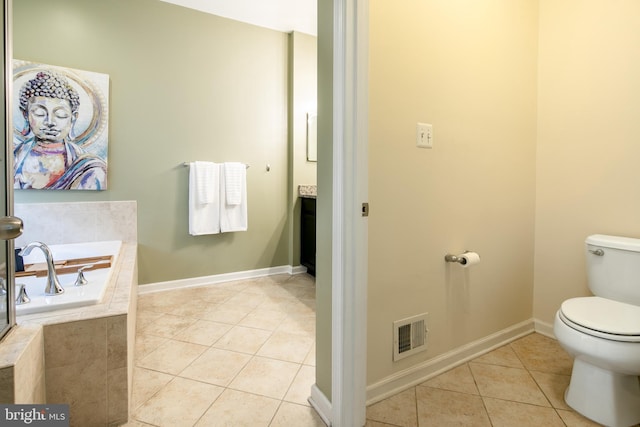 bathroom featuring toilet, a relaxing tiled tub, vanity, and tile patterned flooring