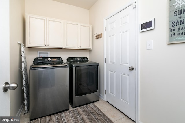 laundry area featuring light tile patterned floors, washing machine and dryer, and cabinets