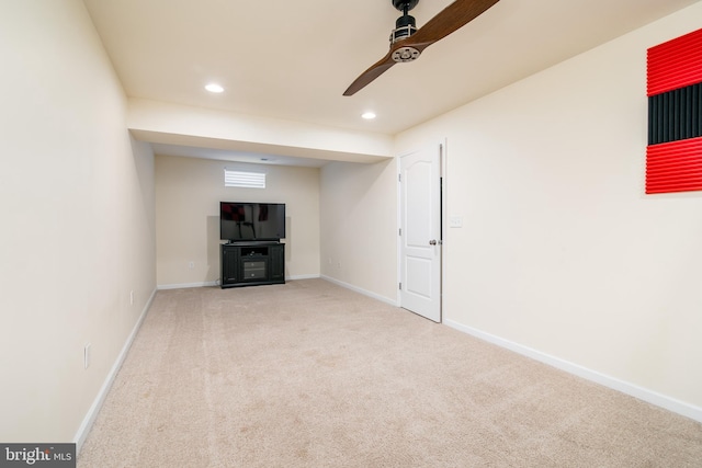 basement with ceiling fan and light colored carpet