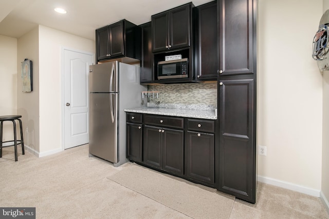 kitchen with light stone countertops, light carpet, appliances with stainless steel finishes, and decorative backsplash