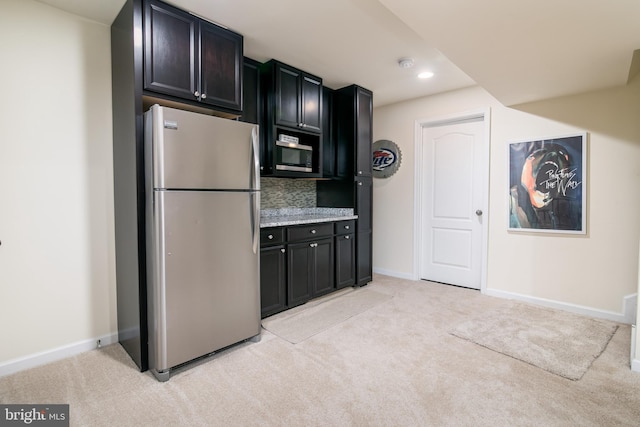 kitchen featuring stainless steel appliances, decorative backsplash, and light colored carpet