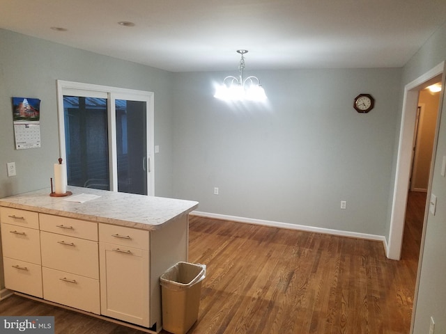 kitchen featuring kitchen peninsula, hardwood / wood-style flooring, hanging light fixtures, and a notable chandelier