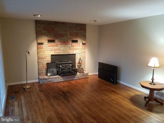 unfurnished living room with wood-type flooring and a wood stove