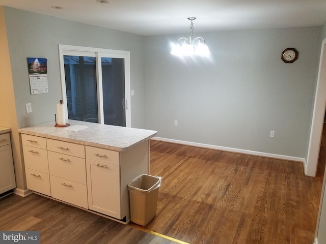 kitchen with kitchen peninsula, pendant lighting, an inviting chandelier, and dark wood-type flooring