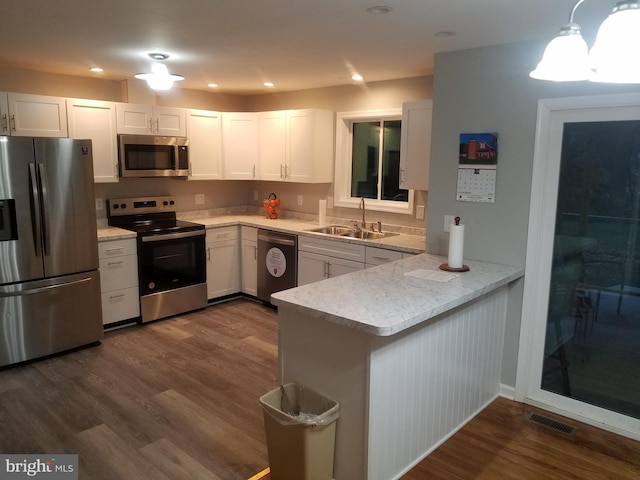 kitchen with sink, white cabinetry, dark hardwood / wood-style flooring, kitchen peninsula, and stainless steel appliances