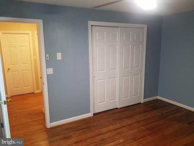 unfurnished bedroom featuring dark hardwood / wood-style flooring and a closet