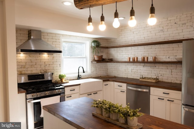 12507 Greenly St, Silver Spring, MD 20906 - kitchen with butcher block countertops, appliances with stainless steel finishes, wall chimney range hood, a sink, and backsplash