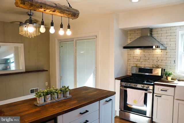 12507 Greenly St, Silver Spring, MD 20906 - kitchen with butcher block counters, stainless steel range with gas stovetop, wall chimney range hood, white cabinetry, and tasteful backsplash