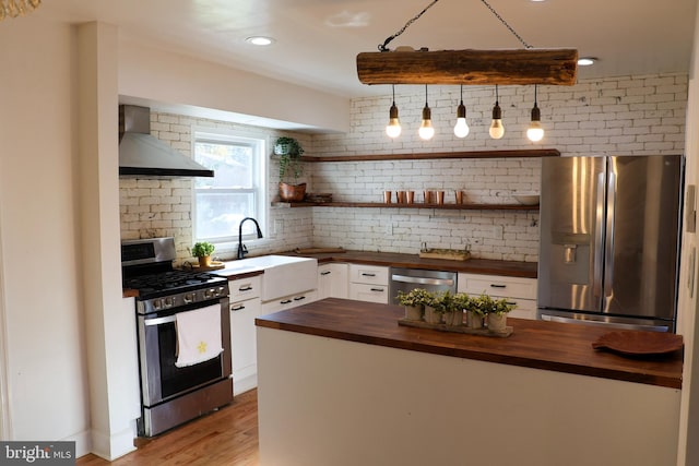 12507 Greenly St, Silver Spring, MD 20906 - kitchen with butcher block countertops, stainless steel appliances, wall chimney exhaust hood, white cabinets, and a sink