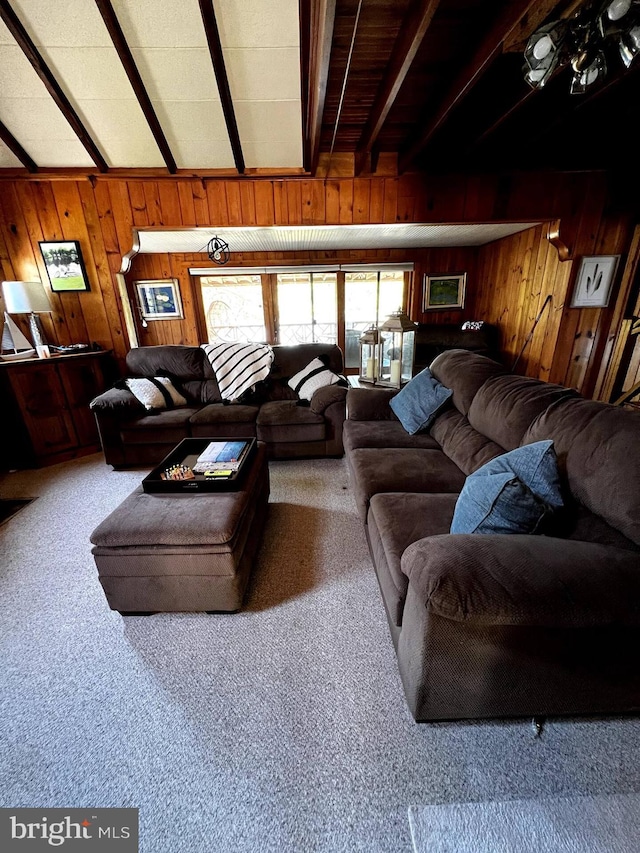 living room with beam ceiling, wooden walls, and carpet