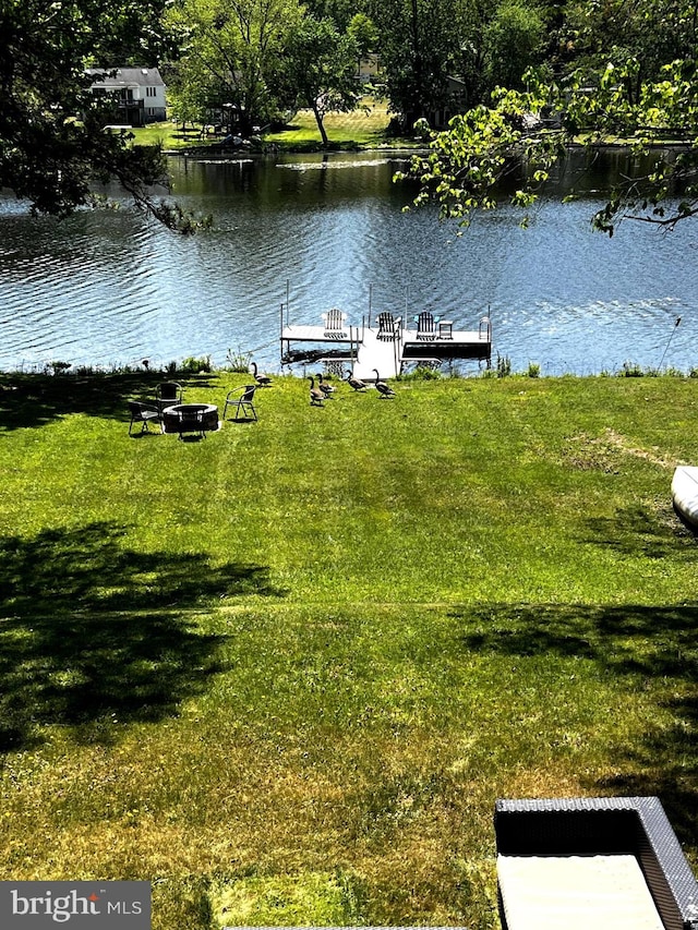 view of dock with a water view and a lawn