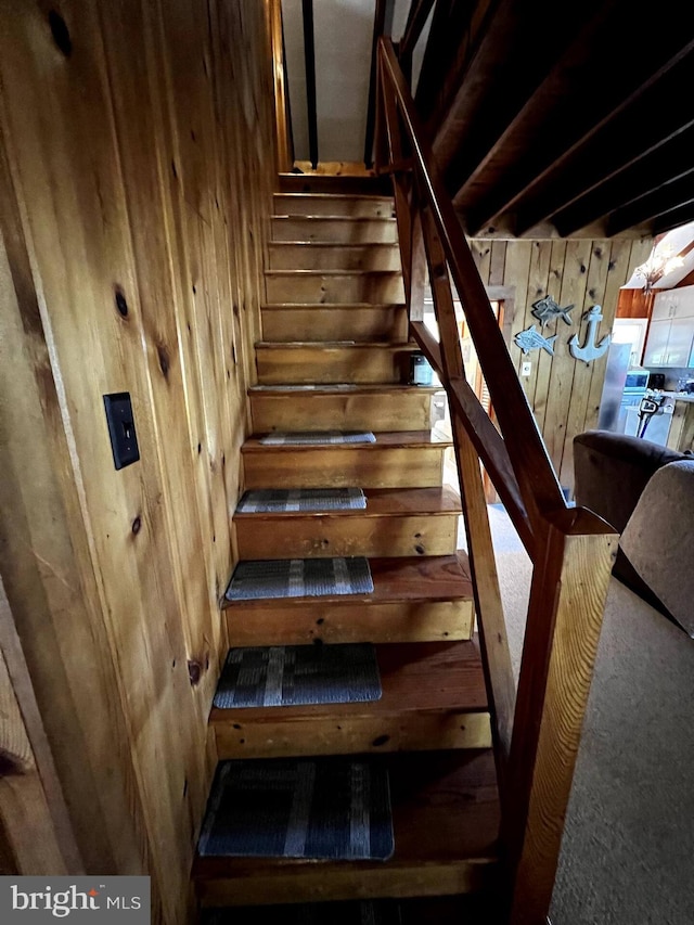 stairway featuring wooden walls