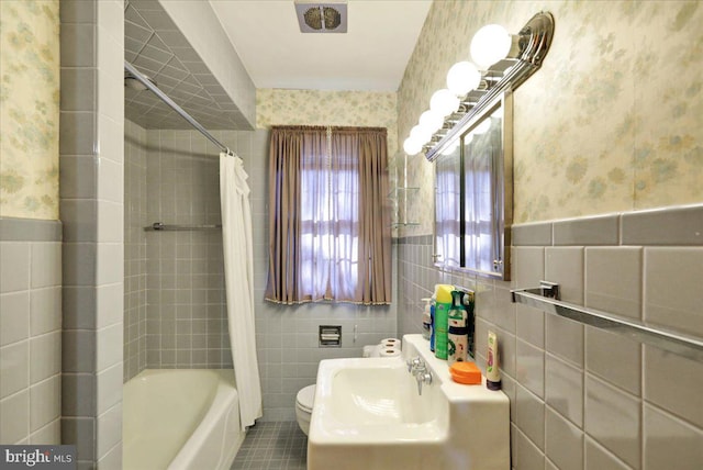 bathroom with toilet, shower / bath combo, and tile walls