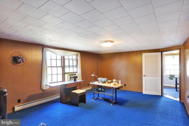 interior space featuring carpet, a baseboard heating unit, and wood walls