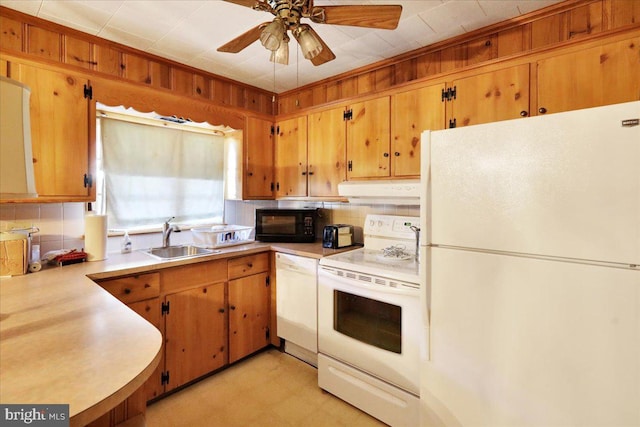 kitchen featuring white appliances, sink, ceiling fan, wooden walls, and decorative backsplash