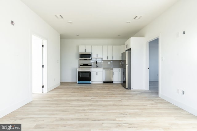 kitchen with white cabinetry, backsplash, appliances with stainless steel finishes, and light wood-type flooring