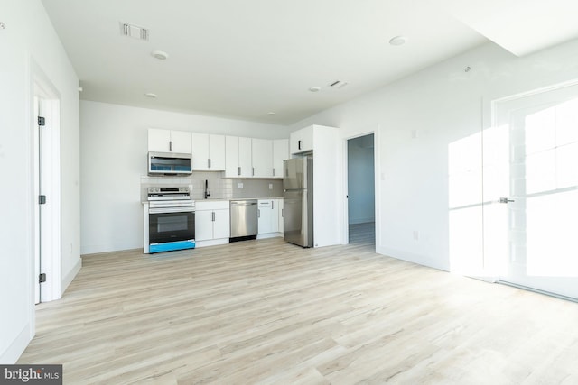 kitchen with sink, white cabinetry, light hardwood / wood-style floors, stainless steel appliances, and tasteful backsplash