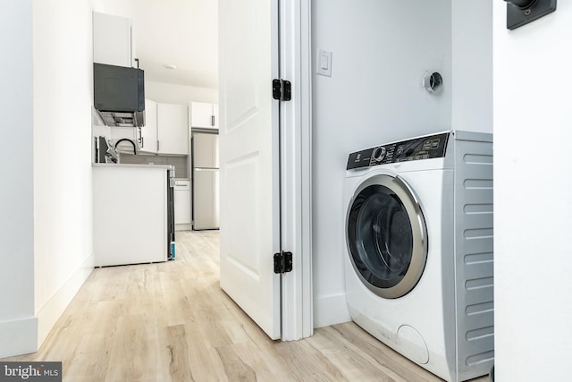 laundry area with sink, washer / clothes dryer, and light hardwood / wood-style flooring