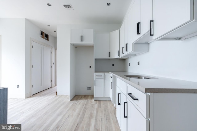 kitchen with light hardwood / wood-style flooring and white cabinetry