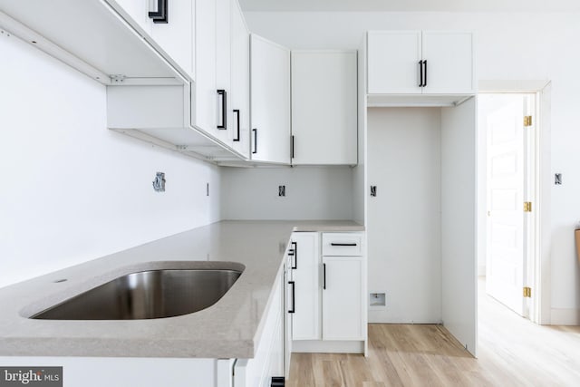 kitchen with light wood-type flooring, white cabinetry, and light stone counters