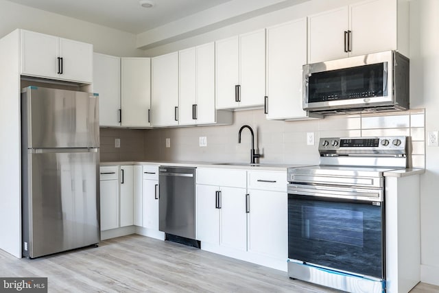 kitchen with sink, stainless steel appliances, white cabinetry, and tasteful backsplash