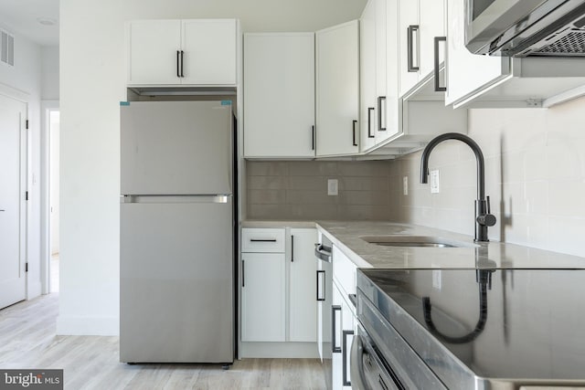 kitchen featuring sink, refrigerator, white cabinetry, electric range, and decorative backsplash