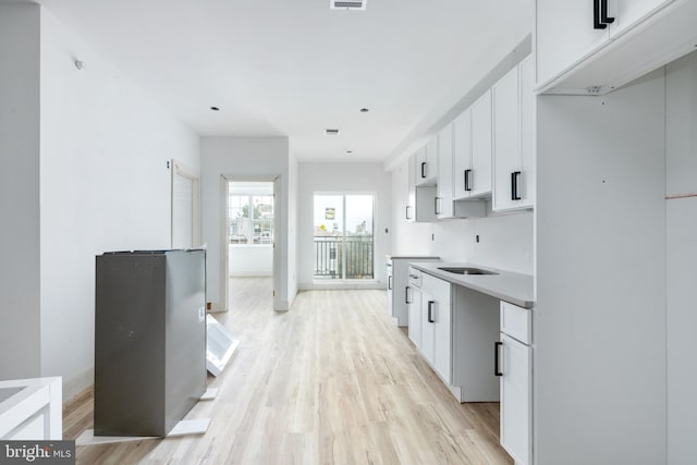 kitchen with light wood-type flooring and white cabinets