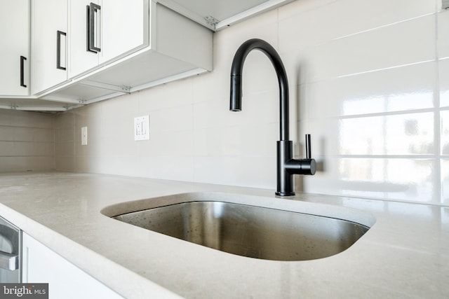 interior details featuring sink, tasteful backsplash, and white cabinets