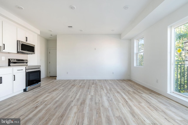 kitchen featuring white cabinets, light hardwood / wood-style floors, appliances with stainless steel finishes, and plenty of natural light