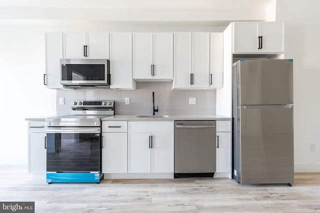 kitchen featuring decorative backsplash, white cabinetry, stainless steel appliances, and sink