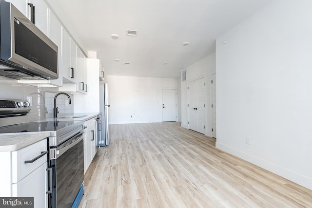 kitchen with white cabinetry, appliances with stainless steel finishes, sink, and light hardwood / wood-style floors