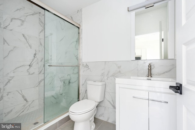 bathroom with tile walls, toilet, vanity, and a shower with shower door