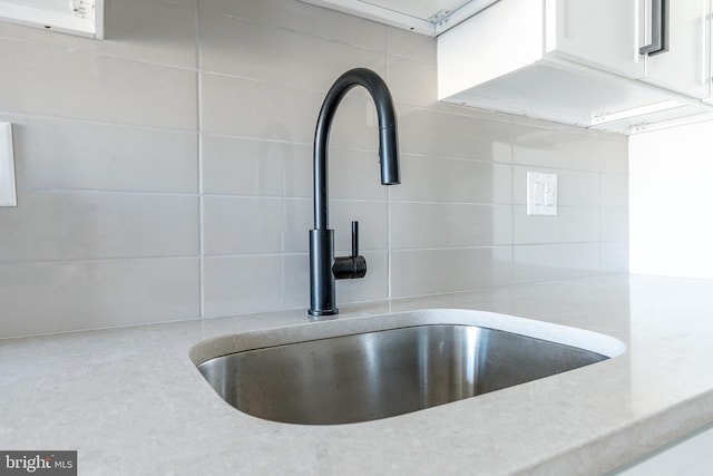 details with sink, tasteful backsplash, and white cabinets