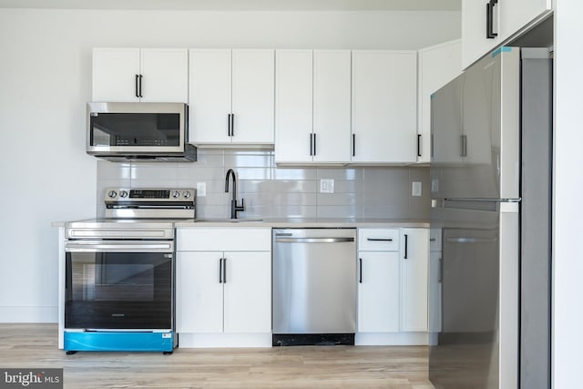 kitchen with sink, backsplash, appliances with stainless steel finishes, and white cabinets