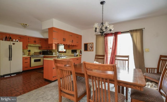 interior space featuring an inviting chandelier, kitchen peninsula, a wealth of natural light, and white appliances