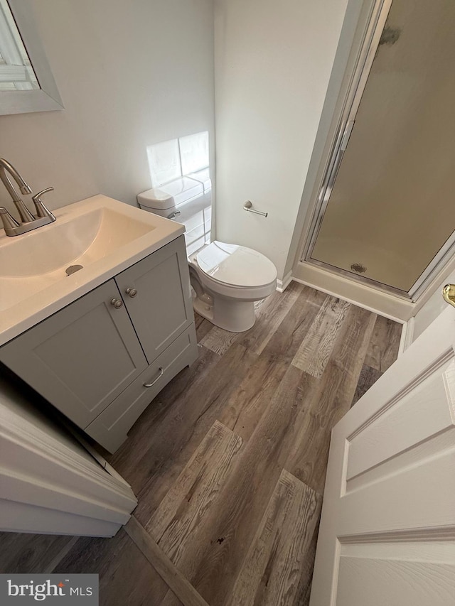 bathroom with wood-type flooring, toilet, an enclosed shower, and vanity