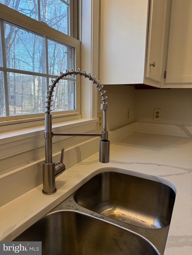 details featuring white cabinetry, sink, and light stone counters