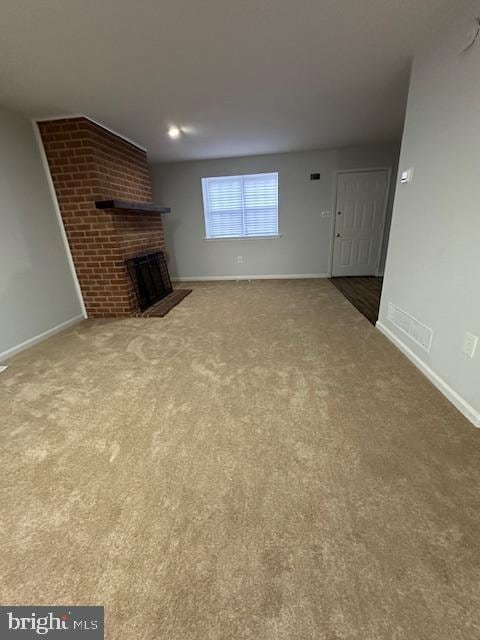 unfurnished living room with carpet flooring and a fireplace