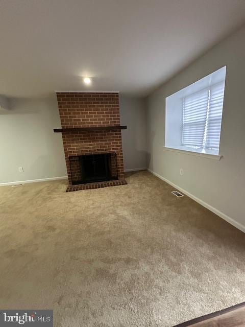 unfurnished living room with carpet floors and a brick fireplace