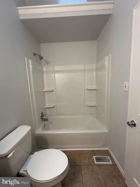 bathroom featuring tile patterned floors, washtub / shower combination, and toilet