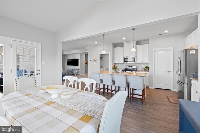 dining area featuring light wood-type flooring and vaulted ceiling