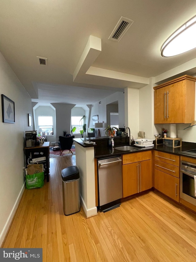 kitchen featuring sink, appliances with stainless steel finishes, light hardwood / wood-style flooring, and kitchen peninsula