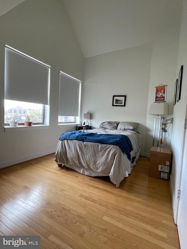 bedroom featuring high vaulted ceiling and light wood-type flooring