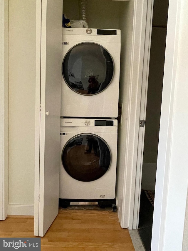 laundry room featuring stacked washer and dryer and light wood-type flooring